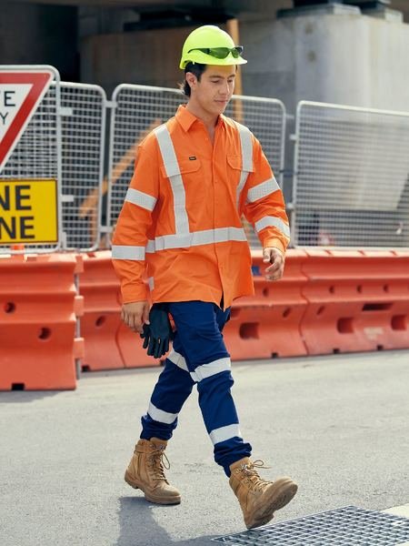 person wearing high-vis gear, the pants are a navy blue with reflective stripes, the shirt is orange with high vis stripes, and they have a yellow high vis hard hat on