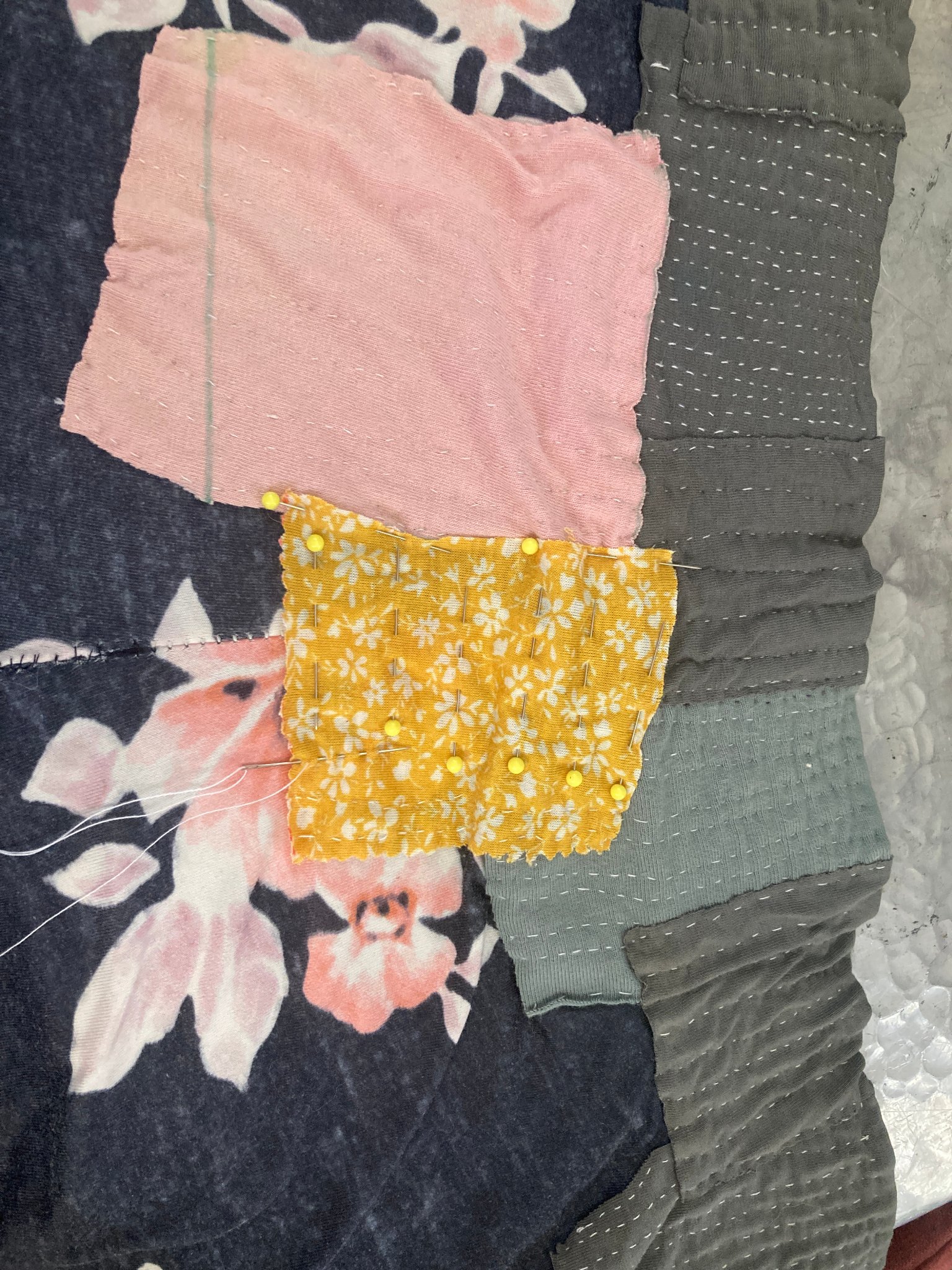 a pair of grey and pink pants with patches sewn on to it (in progress)