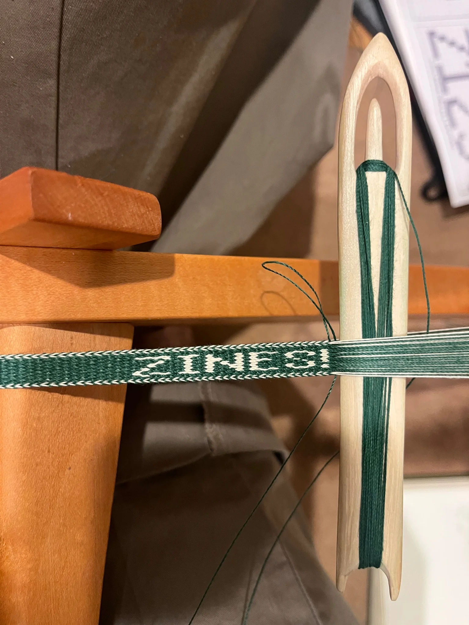 Section of a green woven band with white text reading 'ZINES!'