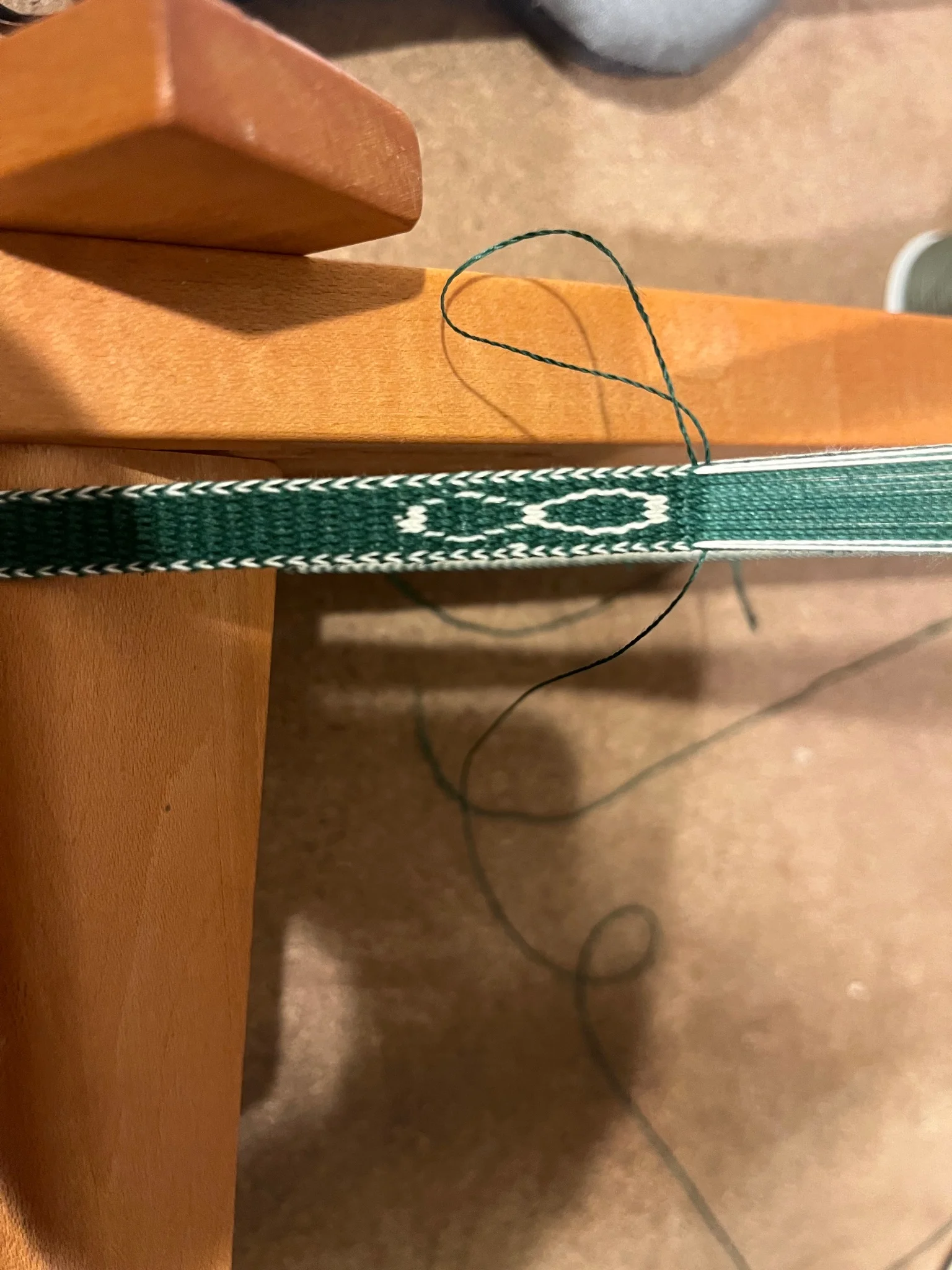 section of a green and white woven band with an infinity symbol