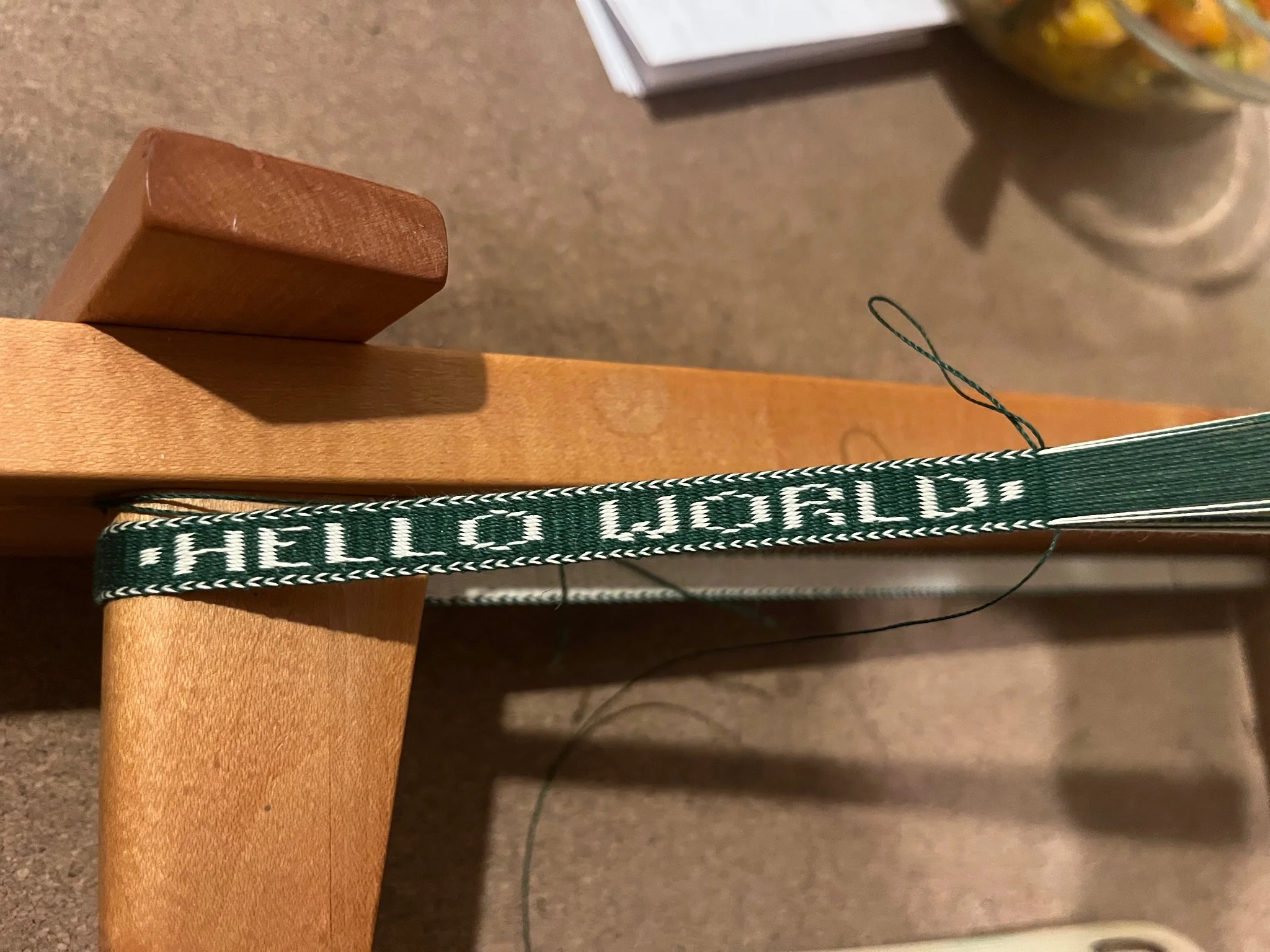 Section of a green woven band with white text reading 'Hello World'
