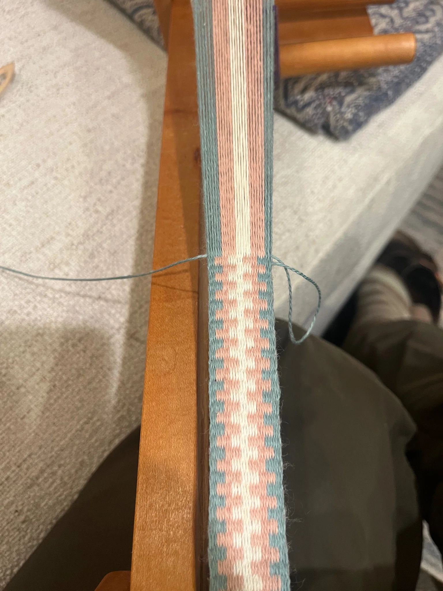 A woven band in progress in the colors of the trans pride flag, light blue, light pink, and white