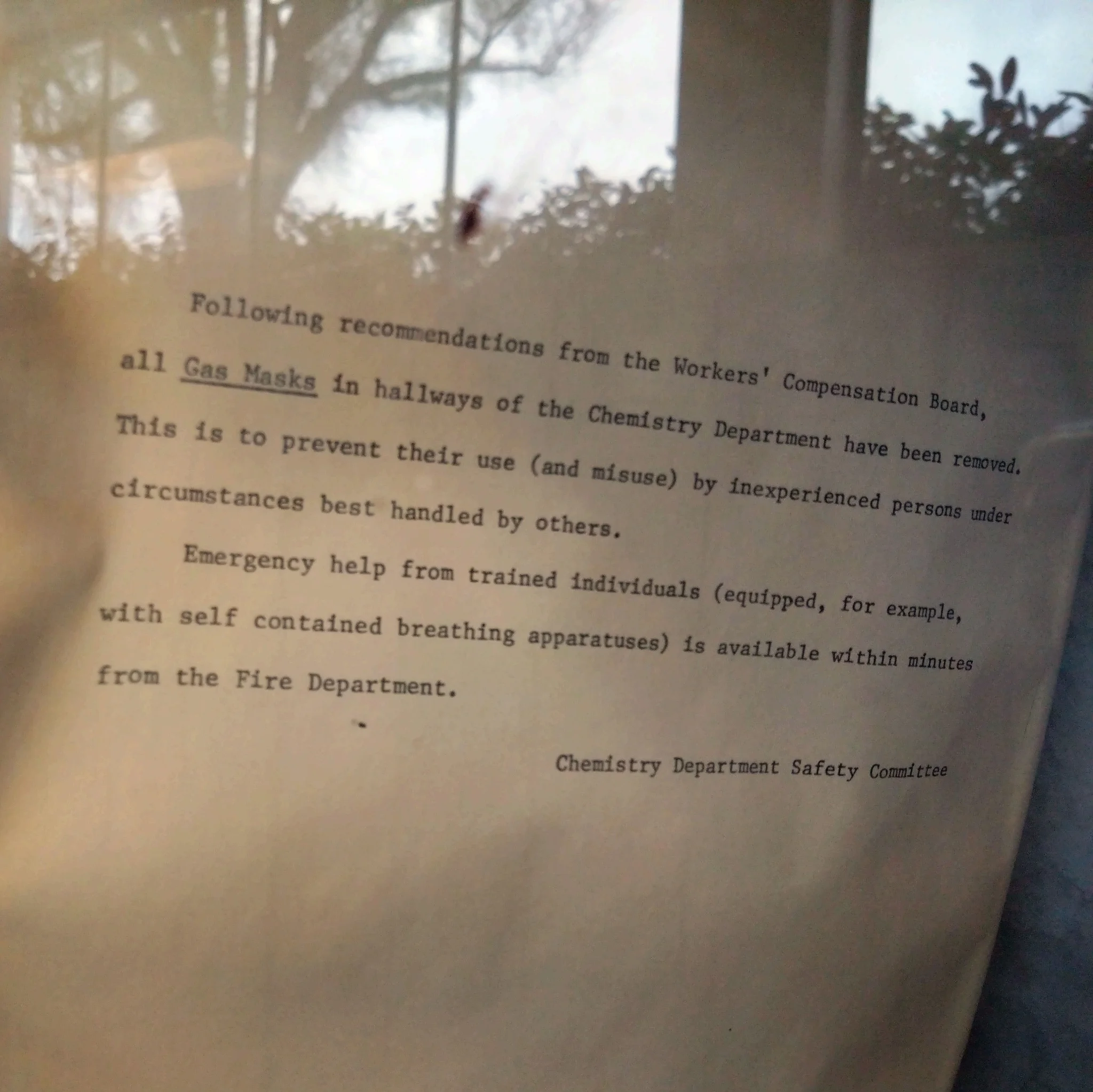A piece of yellowed paper with the following text in typewriter font:

Following recommendations from the Workers' Compensation Board, all Gas Masks in hallways of the Chemistry Department have been removed. This is to prevent their use (and misuse) by inexperienced persons under circumstances best handled by others.
Emergency help from trained individuals (equipped, for example, with self contained breathing apparatus) is available within minutes from the Fire Department.

Chemistry Department Safety Committee