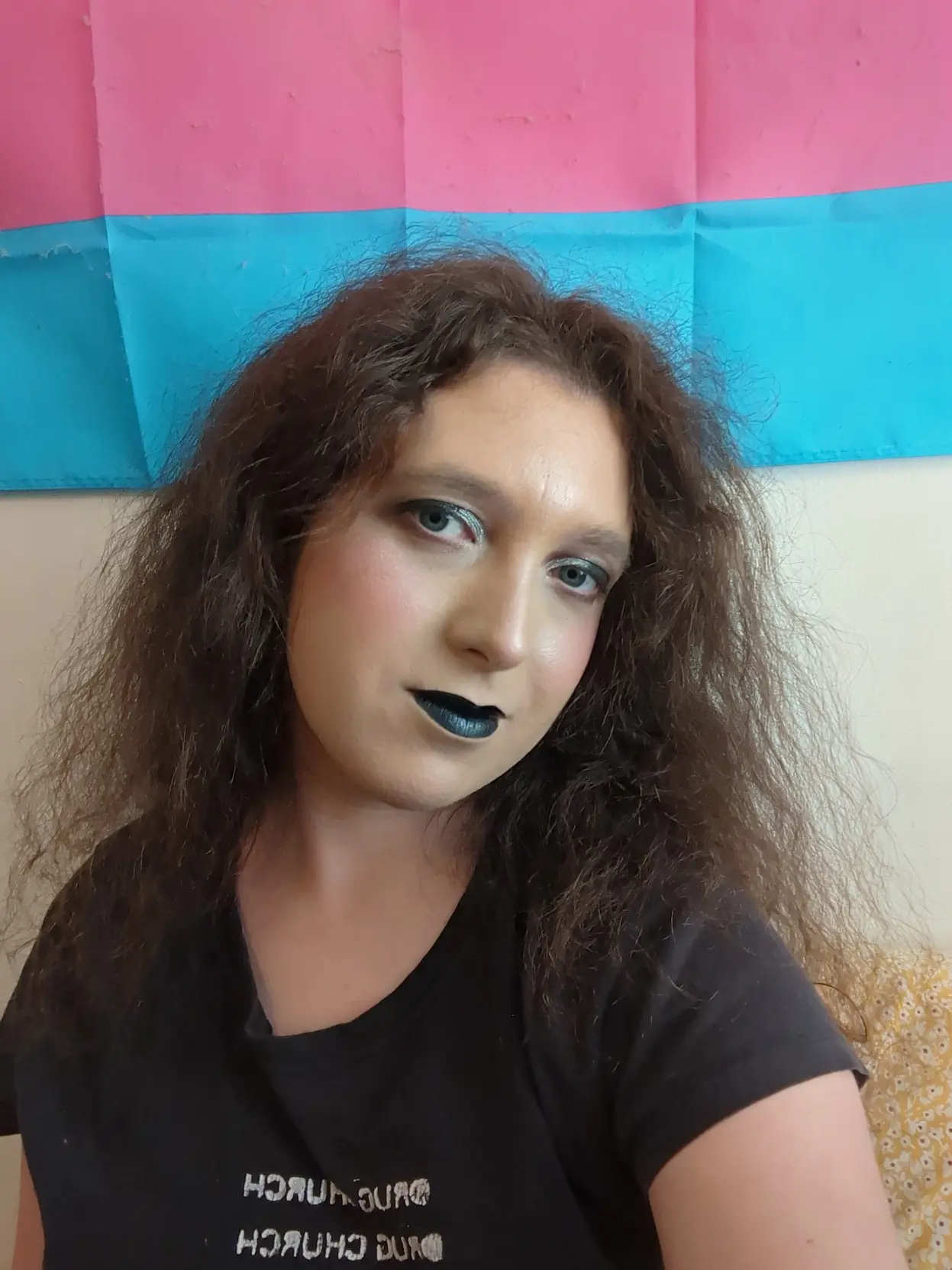 Pale transfem wears goth makeup with black and silver eyeshadow and black lipstick